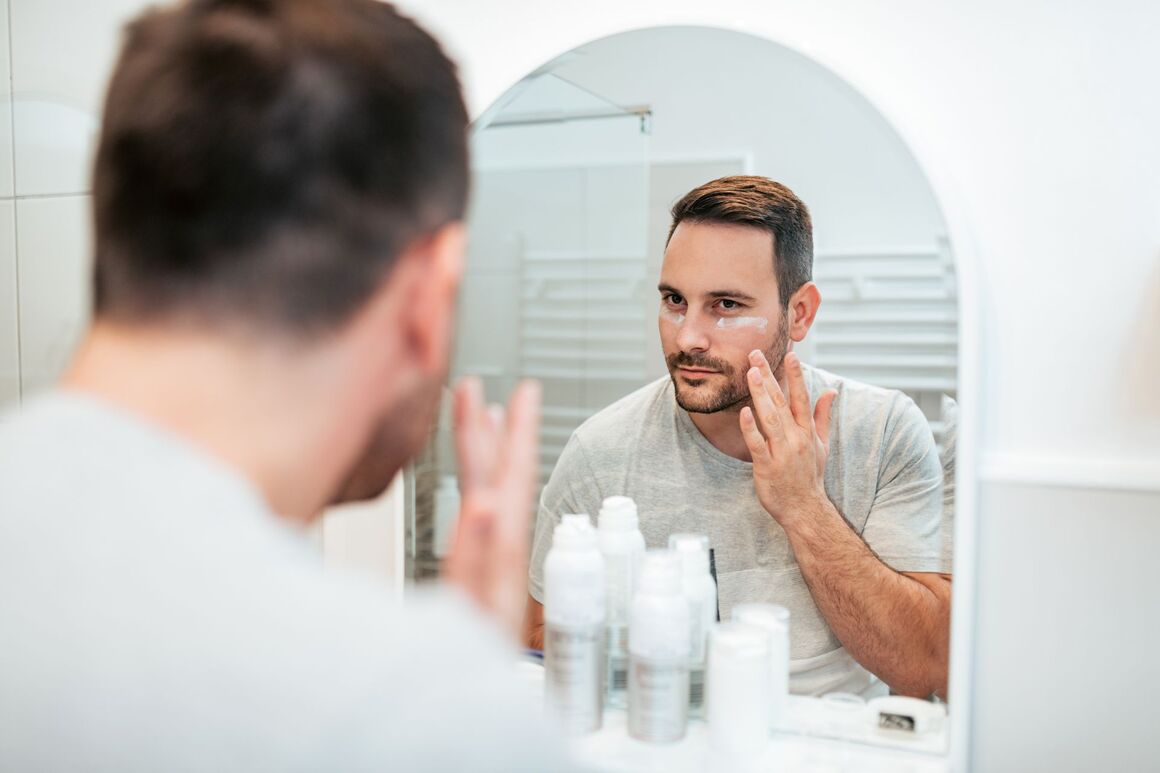 Mann pflegt seine Haut vor dem Spiegel