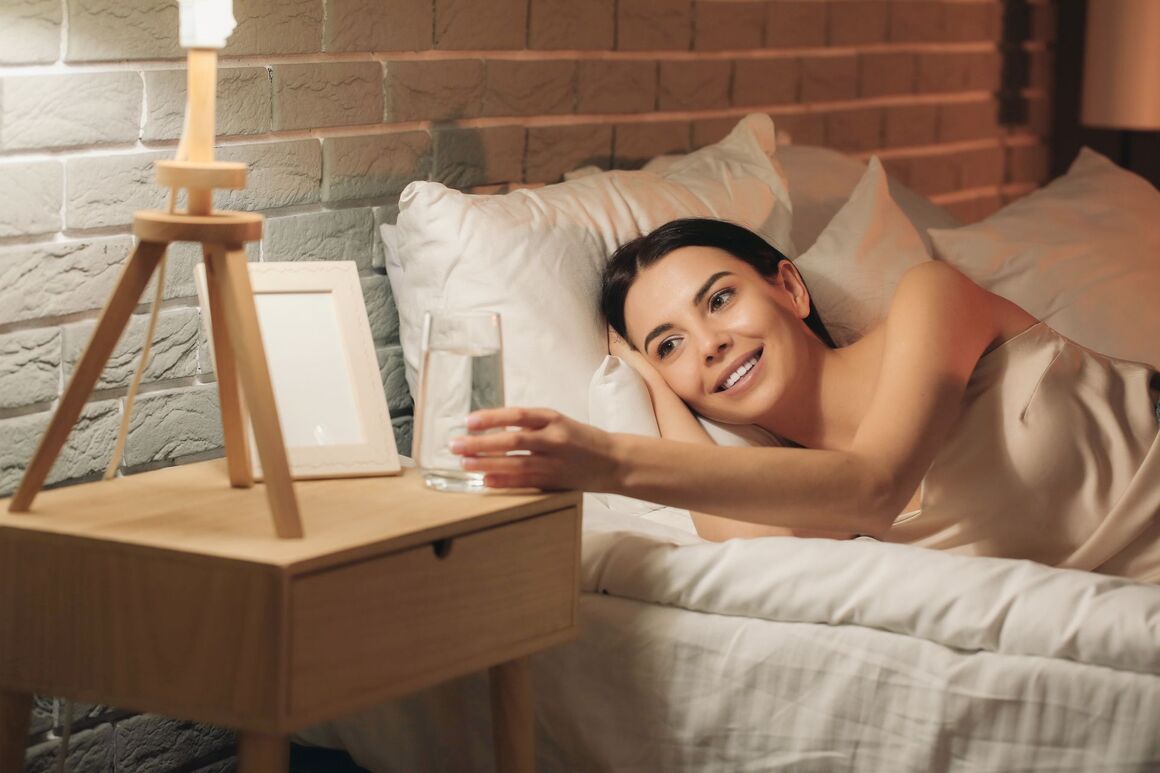 Frau im Bett mit Wasserglas